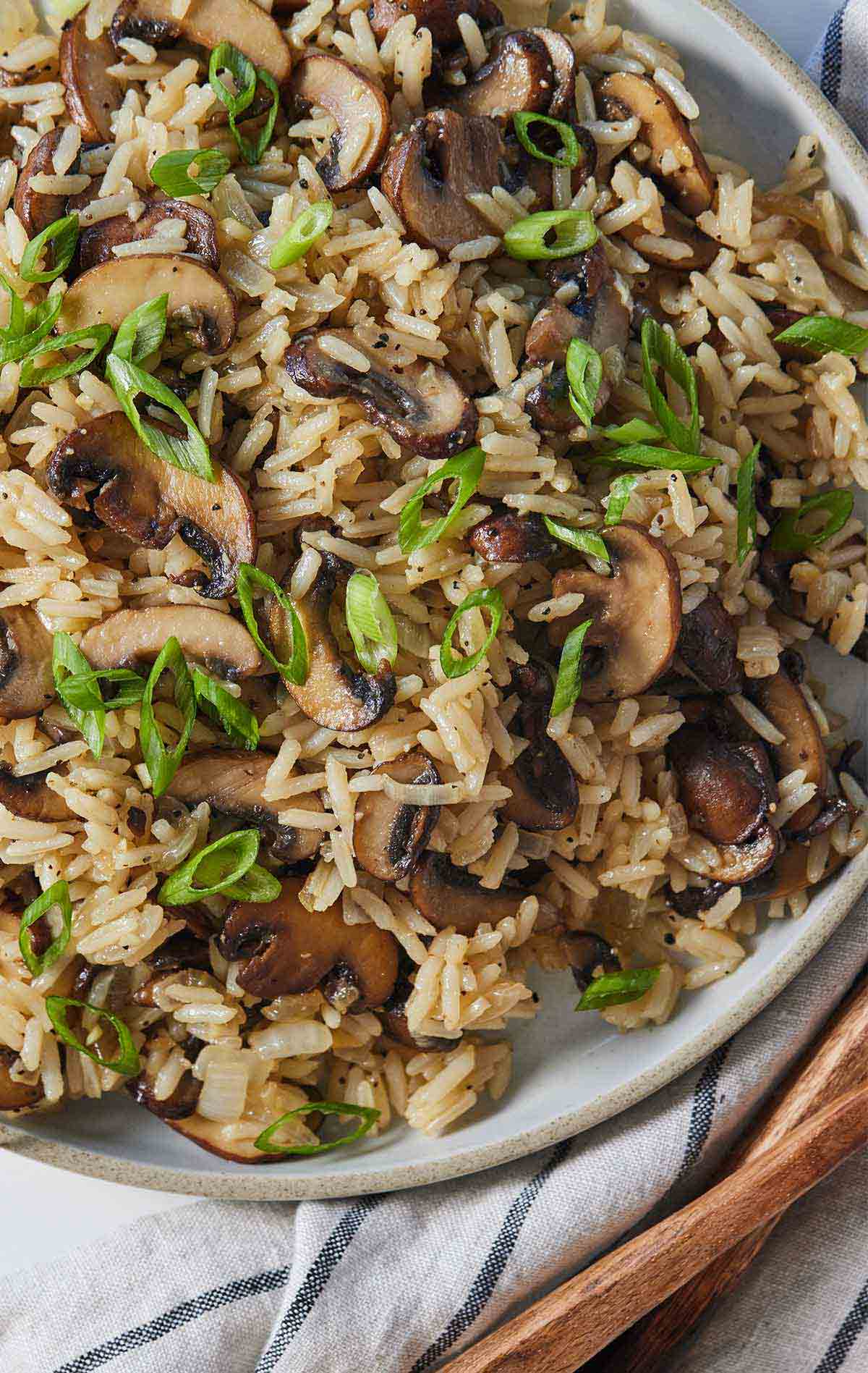 Overhead view of a plate of mushroom rice with sliced green onions on top.