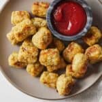 Overhead view of a bowl of cauliflower tater tots with ketchup on the side.