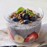 A serving of chia pudding in a bowl with fresh fruits, granola, and mint.