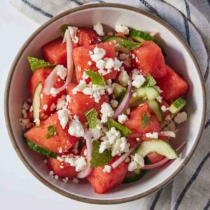 Overhead view of a bowl of watermelon salad with fresh mint leaves on top.