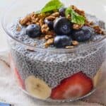Pinterest graphic of a bowl of chia pudding with banana slices, strawberry slices, blueberries, granola, and mint leaves.