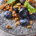 Pinterest graphic of the close up image of chia pudding with blueberries, mint leaves, and granola on top.
