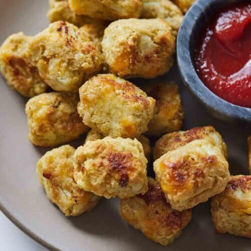 Overhead view of a plate of cauliflower tater tots with a side of ketchup.