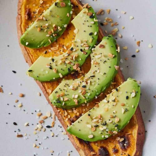 Overhead view of a sweet potato toast with sliced avocado on top.