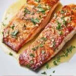 Pinterest graphic of two pan seared salmon with butter sauce on top.