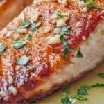 Pinterest graphic of the close up of a fillet with chopped parsley and minced garlic on top.