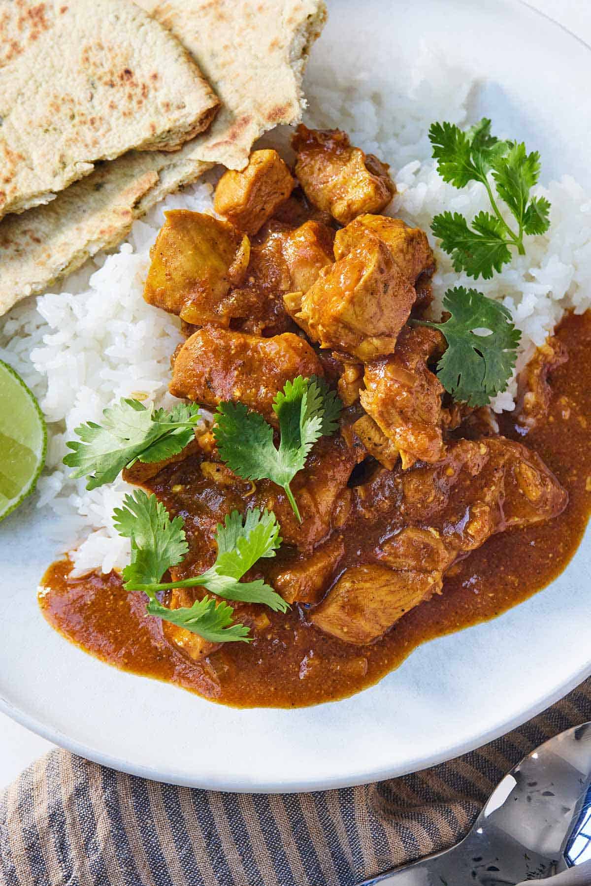 A plate of Instant Pot chicken tikka masala with rice and naan.