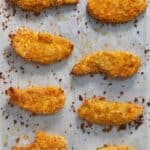 Pinterest graphic of a parchment paper with multiple pieces of chicken tenders.