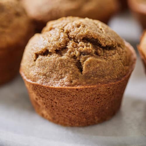 A healthy banana muffin in focus, on a plate.