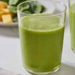 Pinterest graphic of a glass of green smoothie with ingredients in the background.