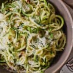 Pinterest graphic of a bowl of zucchini noodles with parmesan sprinkled on top.