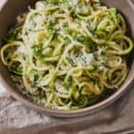 Pinterest graphic of a bowl of zucchini noodles topped with parmesan and chili flakes.