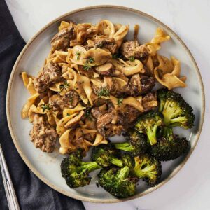 Overhead view of a plate with beef stroganoff with broccoli.
