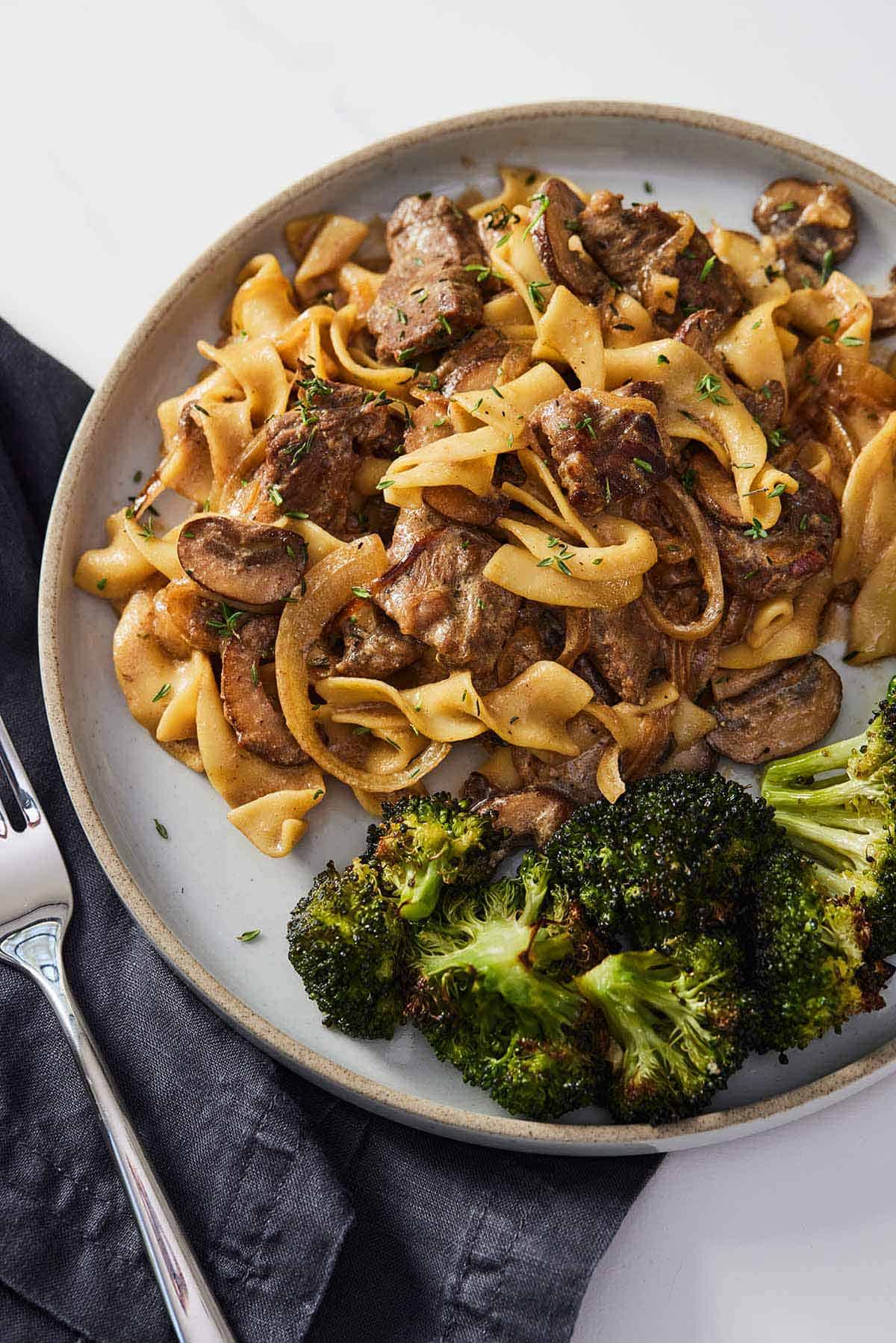 A plate of beef stroganoff with broccoli.