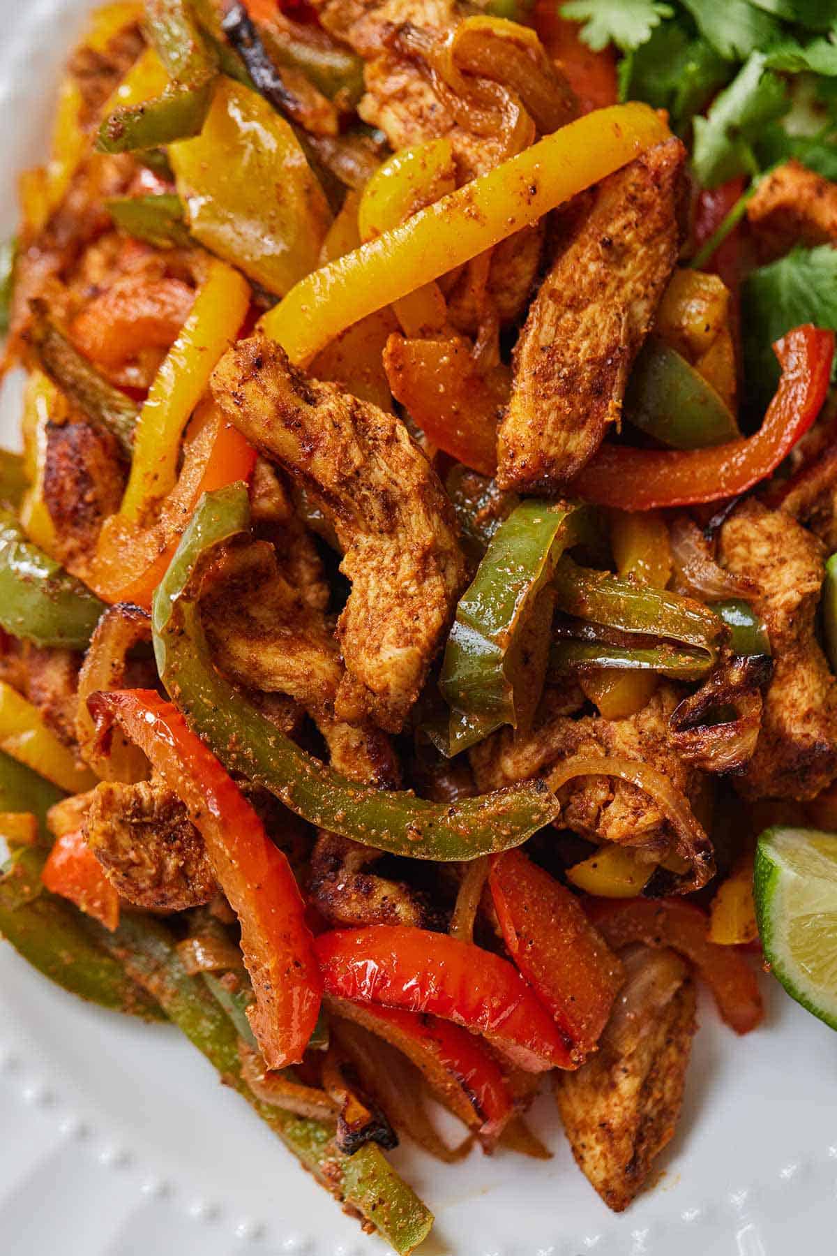 Close up of air fryer chicken fajitas on a white plate.