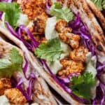 Pinterest graphic of a close up view of a cauliflower taco with shredded cabbage, cilantro, and avocado sauce.