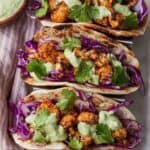 Pinterest graphic of three cauliflower tacos on a taco holder with garnishes on top.