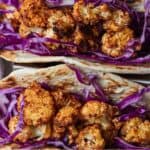 Pinterest graphic of two cauliflower tacos with shredded cabbage.