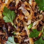 Pinterest graphic of a close up view of mujadara with caramelized onions and parsley on top.