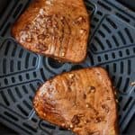Pinterest graphic of two tuna steaks in an air fryer basket.