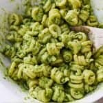 Pinterest graphic of a bowl of avocado pesto pasta with a wooden spoon.