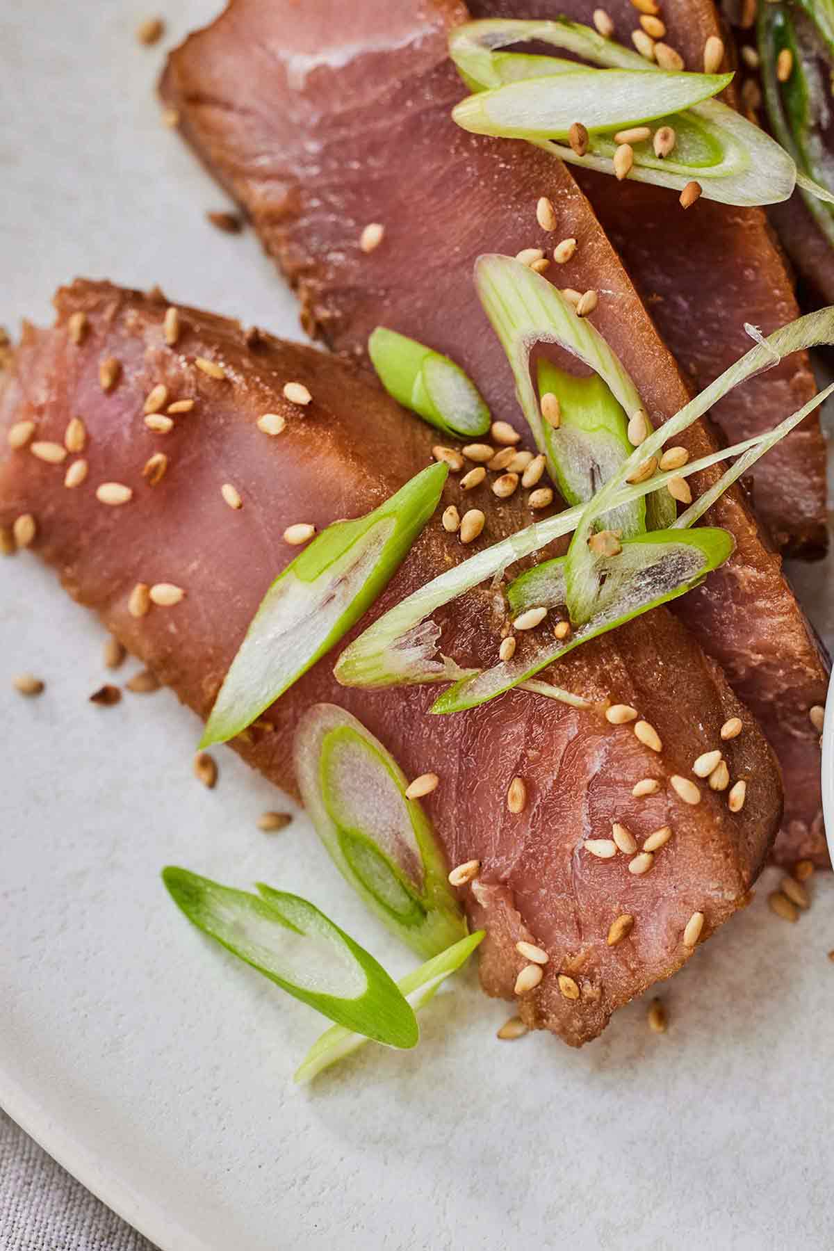 Close up of three slices of air fryer tuna steaks with green onions on top.