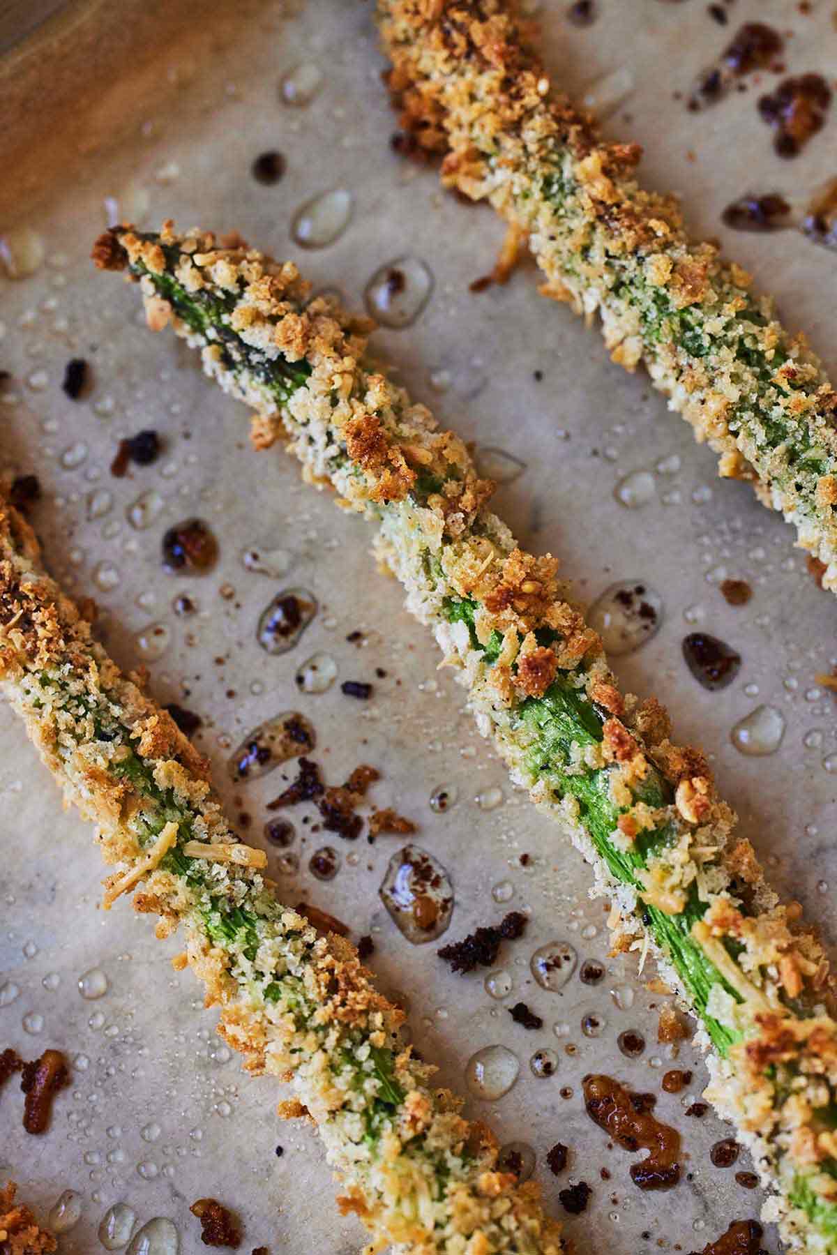 Close up of asparagus fries on a lined sheet pan.