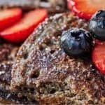 Pinterest graphic of a close up view of buckwheat pancakes with fruit on top.