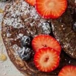 Pinterest graphic of an overhead view of a close view of buckwheat pancakes with berries on top.