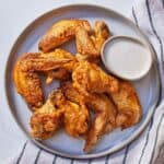 Overhead view of a plate of air fryer chicken wings with a small bowl of dip.