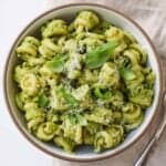 Overhead view of a bowl of avocado pesto pasta with basil on top.