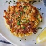 Pinterest graphic of the close up view of a crab cake with parsley on top.