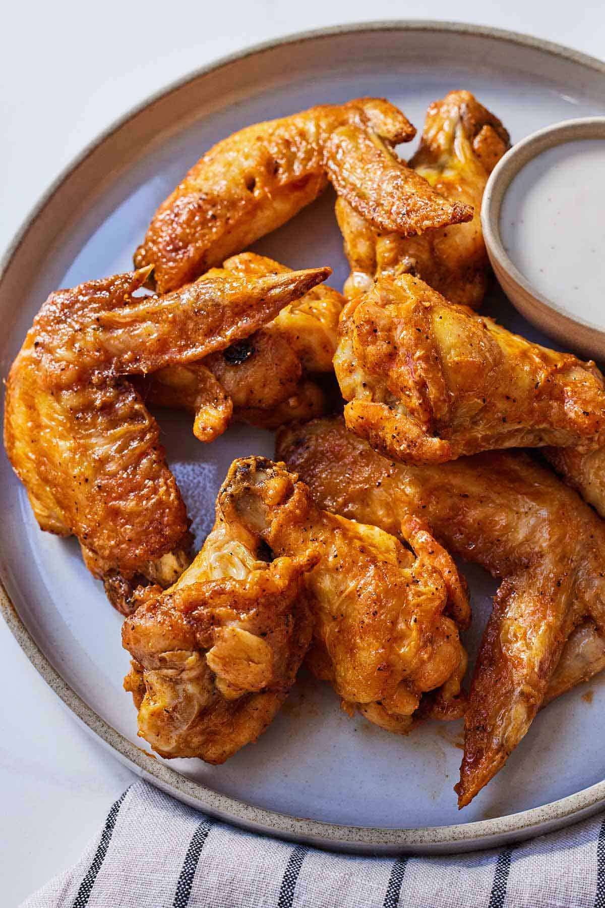 A plate with air fryer chicken wings with dip on the side.