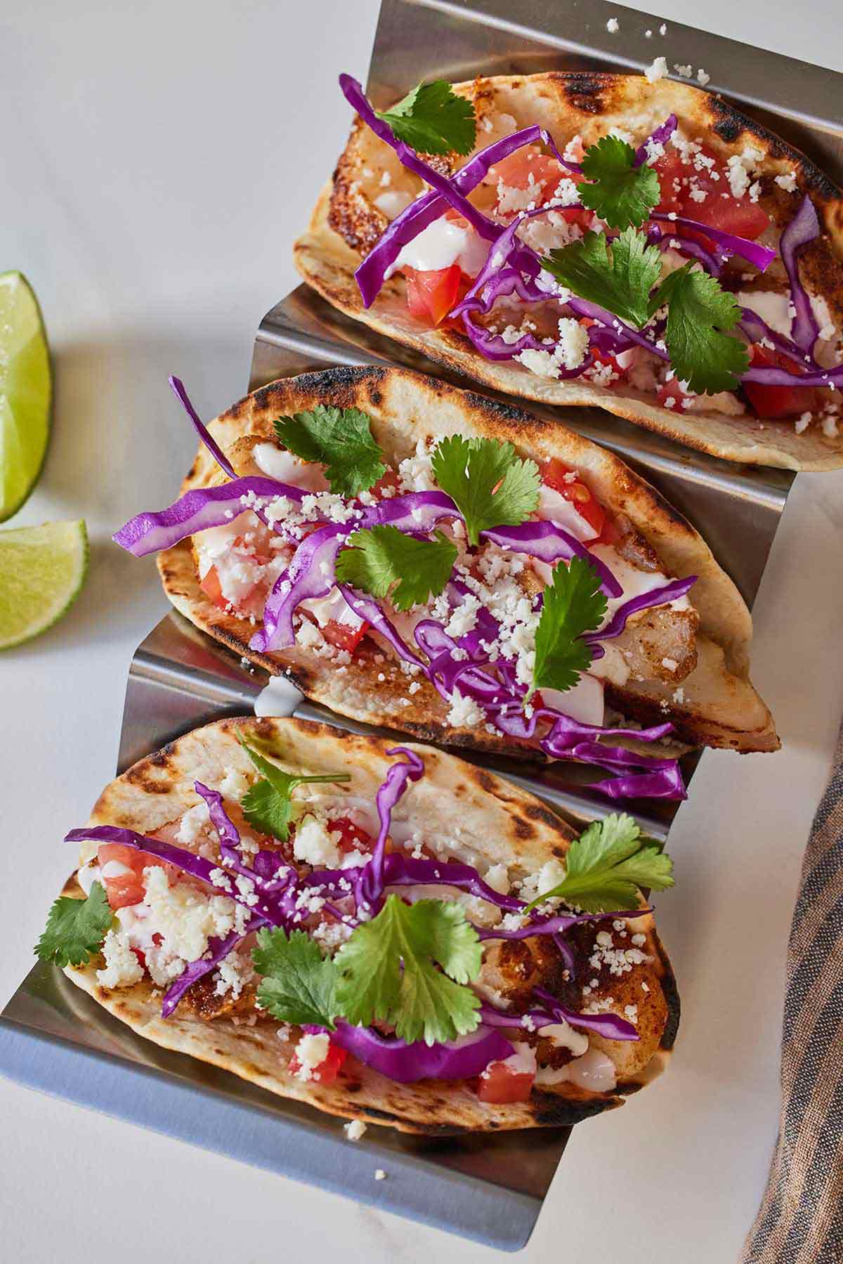 Overhead view of three fish tacos on a taco holder.