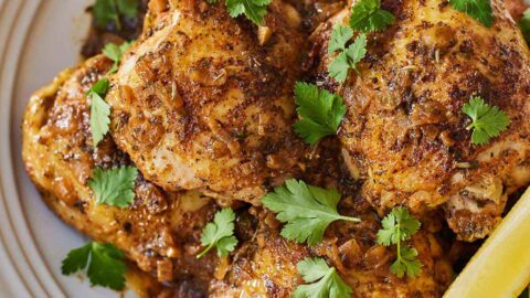 A plate with Instant Pot lemon garlic chicken with herb garnish and a lemon wedge.