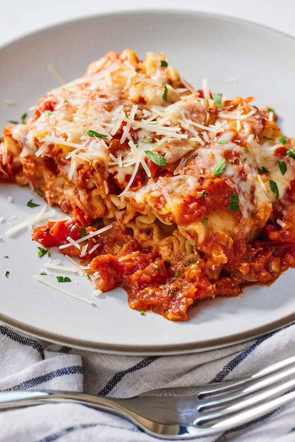 A plate with a serving of lasagna roll ups with a fork in front.