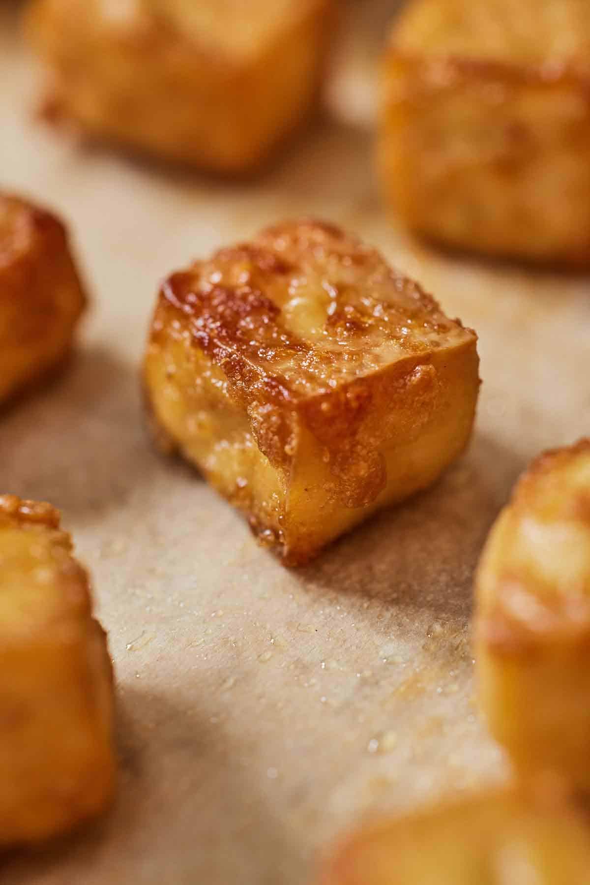 Close up of a baked tofu cube on a baking sheet.
