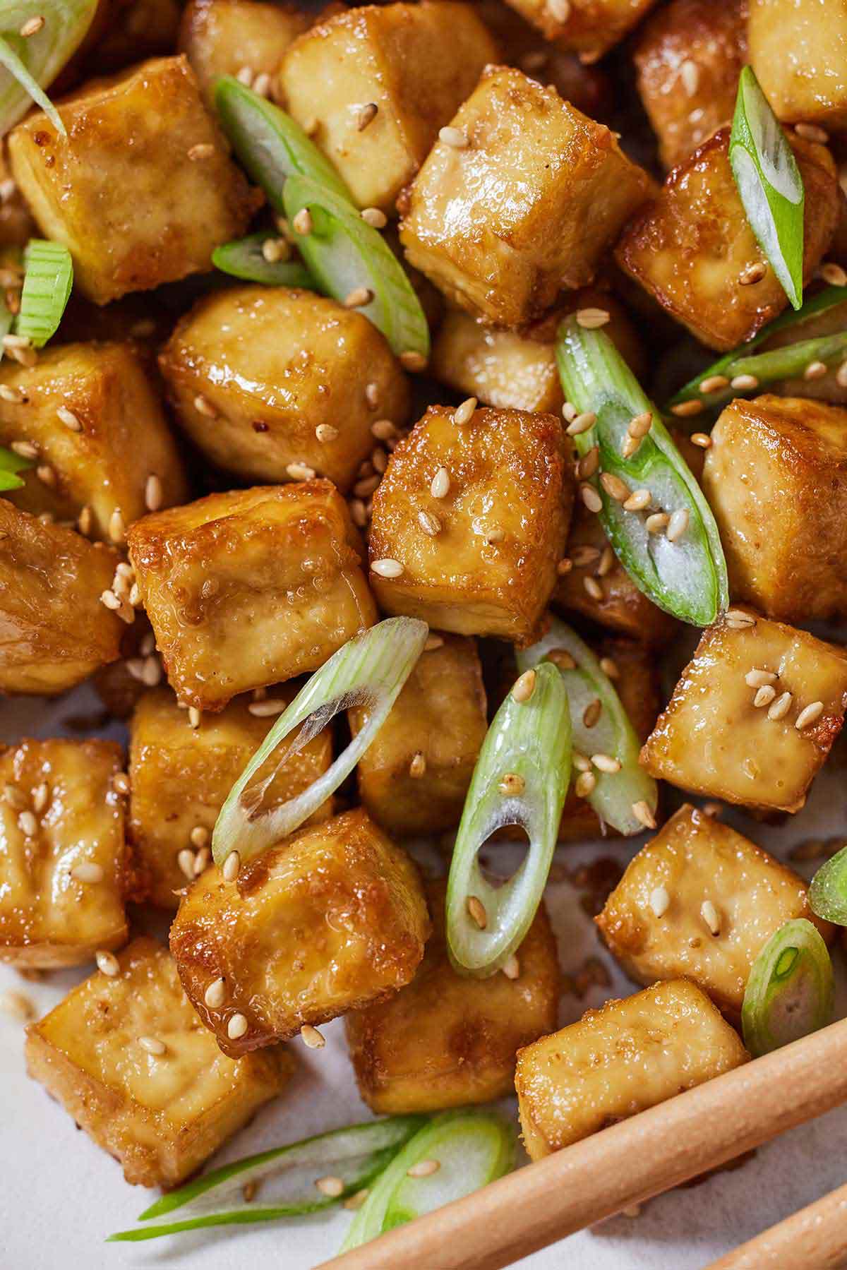 Baked tofu with green onions and sesame seed garnished on top.