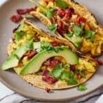 Pinterest graphic of a plate of two breakfast tacos with eggs, bacon, and avocado.