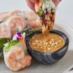 Pinterest graphic of half of a salad rolls dipped into a peanut dipping sauce.