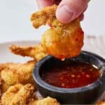 Pinterest graphic of an air fryer coconut shrimp dipped into sweet chili sauce.