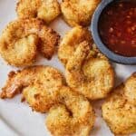 Pinterest graphic of a plate of air fryer coconut shrimp with a small bowl of sweet chili sauce on the side.