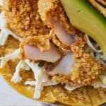Pinterest graphic of fish in an air fryer fish taco cut in half to show the inside.