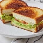 Pinterest graphic of a plate with an avocado grilled cheese cut in half.