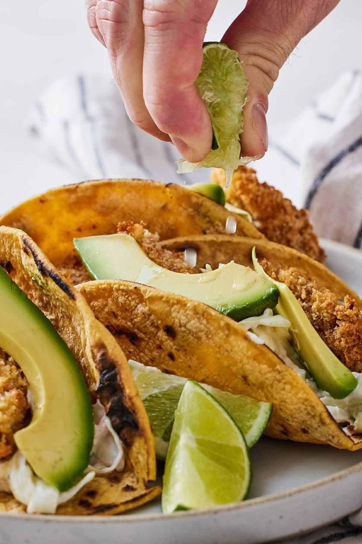 Lime wedge squeezed over a plate of air fryer fish tacos.