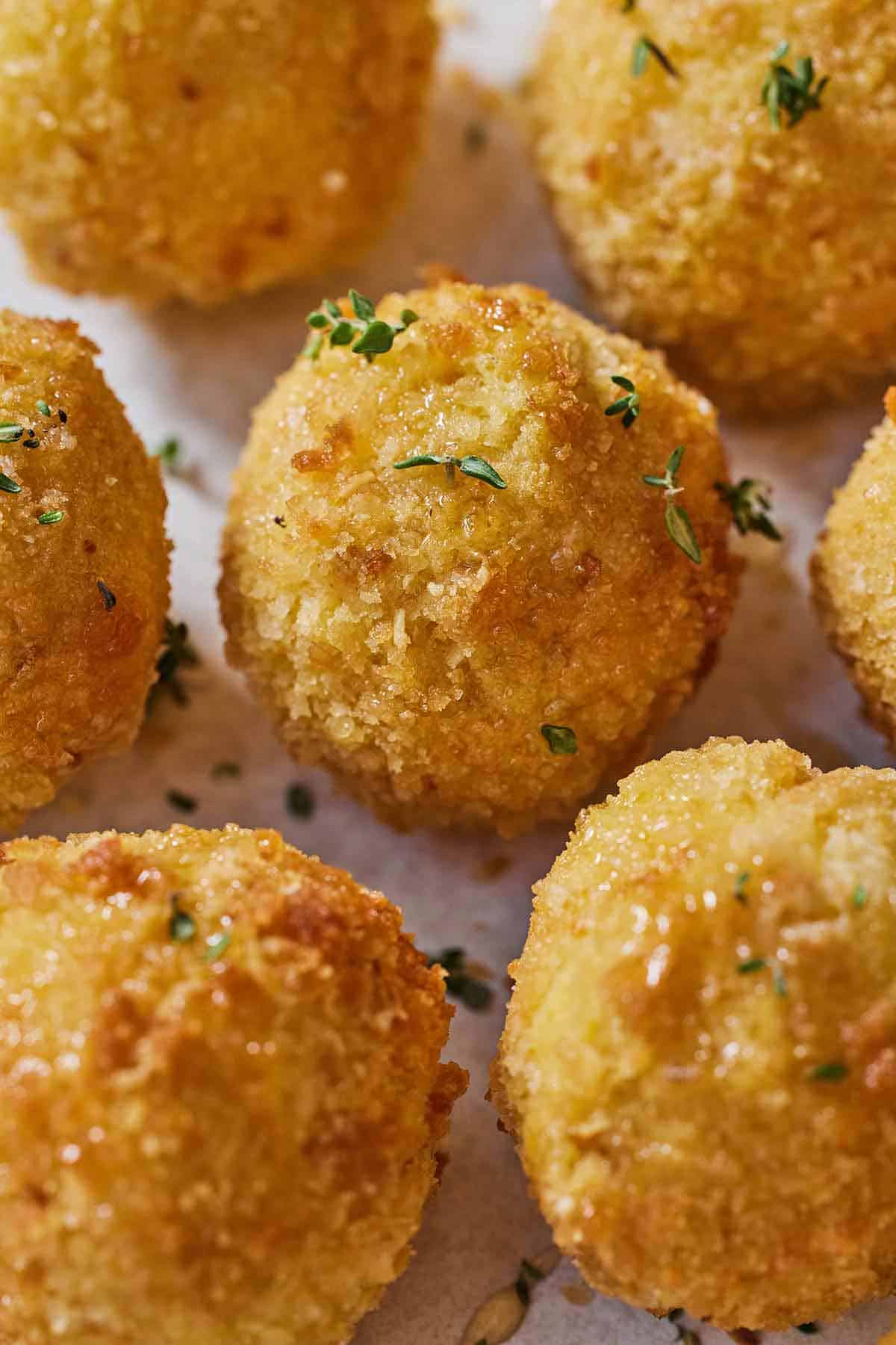 Close up of multiple air fryer goat cheese balls with fresh herbs on top.