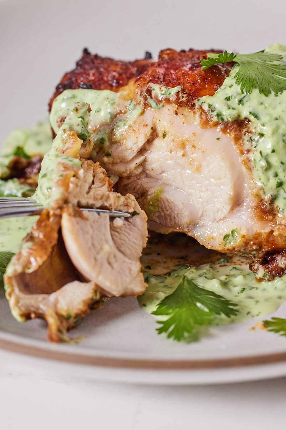 Close up of Peruvian chicken cut open with a piece on a fork, showing the moisture inside the chicken.
