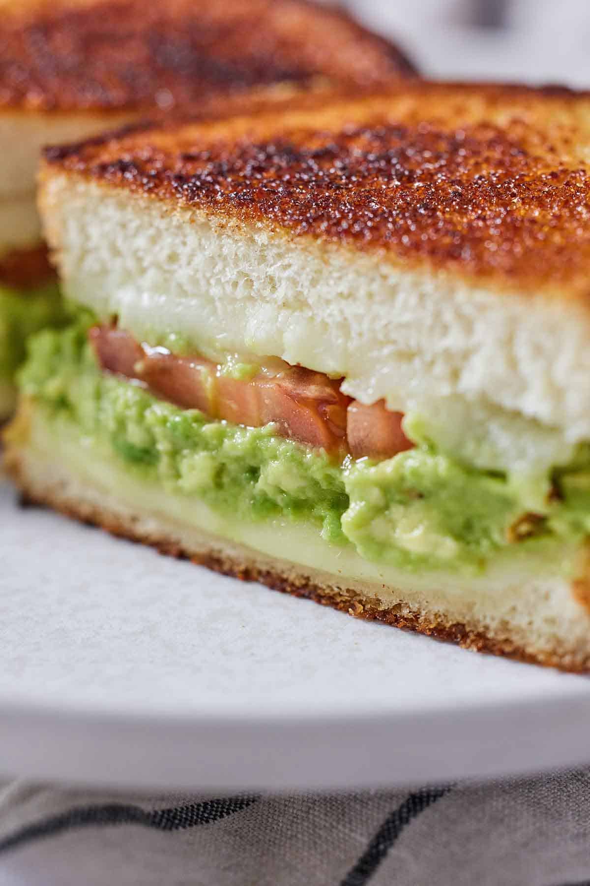 Close up of the cross section of an avocado grilled cheese sandwich, showing the filling.