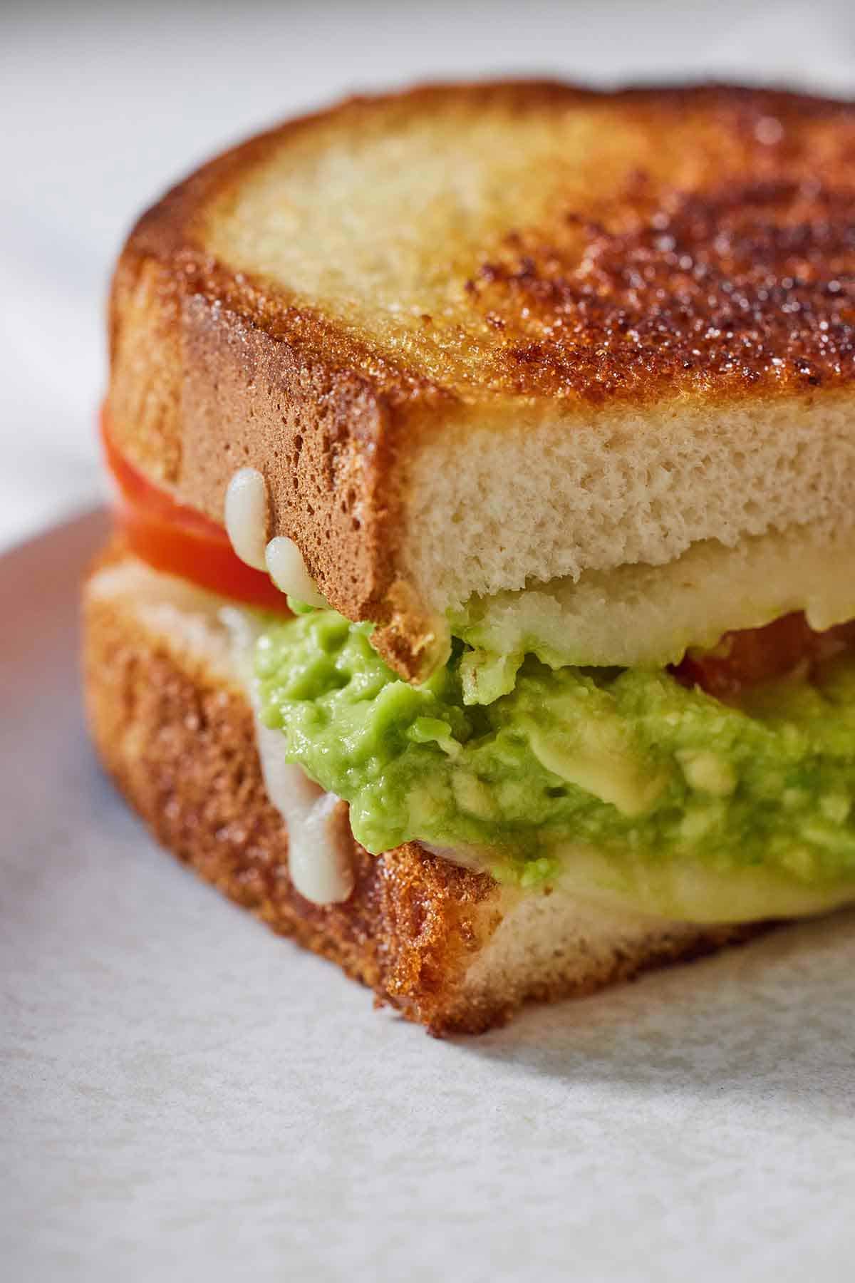 Close up of half of a cut avocado grilled cheese sandwich.