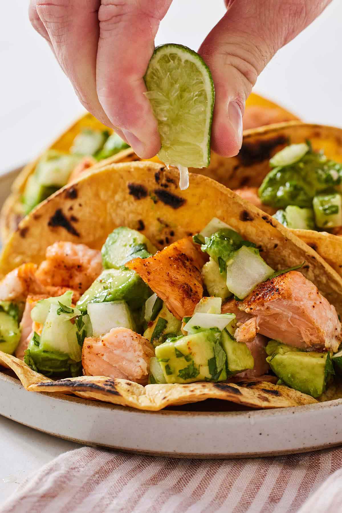 Lime wedge being squeezed over a salmon taco.
